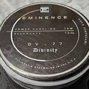 Fotografie zachycuje zadní část reproduktoru s černým krytem magnetu. Na krytu je bílý nápis EMINENCE, logo ve tvaru čtverce a označení DV - 77 Divin…