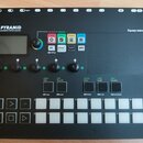 Černý sekvencer s nápisem PYRAMID polyrhythmic 64track sequencer a značkou Squarp instruments. Zařízení obsahuje displej, pět otočných ovladačů, něko…