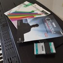 Fotografie zobrazuje část digitálního klavíru, dva manuály a paměťovou kartu. Na modrém manuálu je nápis Yamaha Clavinova CVP-508/16 a text Klassisch…