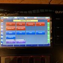 Černý elektronický přístroj s nápisem QUIVER v pravém horním rohu. Uprostřed je displej zobrazený pod ochrannou fólií, na kterém je text Quiver Rel.…