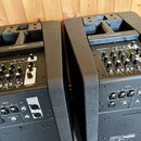 Dva černé aktivní reproduktory značky YAMAHA s texturovaným povrchem. Každý má ovládací panel s několika knoflíky, přepínači a červeným knoflíkem MAS…