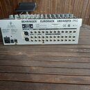 Zadní strana stříbrného míchacího pultu s nápisem BEHRINGER® EURORACK UB2442FX-PRO. Jsou zde viditelné různé typy konektorů, včetně vstupů a výstupů…