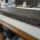 Černý grafický ekvalizér v rackovém provedení s řadou posuvníků. Na levé straně je logo "dbx" a vpravo nápis "GRAPHIC EQUALIZER" vedle vypínače s pop…