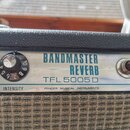 Detail kytarového zesilovače s černým povrchem a kovovým ovládacím panelem. Na panelu je modrý nápis BANDMASTER REVERB a pod ním černý kód TFL 5005 D…