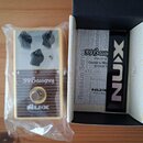 Kremově bílý efekt pedál s dřevěnou přední deskou a třemi černými oválnými knoflíky. Na pedálu je nápis '59 Bassguy a v dolní části logo NUX s doplňk…