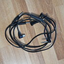 Černý audio kabel s konektory typu jack. Kabel má na koncích různé typy konektorů, včetně jednoho pravúhlého. Na kabelu nejsou žádné viditelné značky…