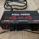 Černý napájecí adaptér pro efektové pedály s nápisy Voodoo Lab, PEDAL POWER a 4x4. Na horní straně jsou uvedeny specifikace výstupů v sekcích HIGH CU…
