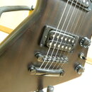 Detail elektrické kytary s tmavým dřevěným povrchem. Nástroj má dva snímače typu humbucker, černý most s kotvami a dva ovládací knofíky s bílými znač…