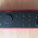 Černý audio rozhraní s červeným rámem. Na horním panelu je nápis Scarlett 16i6 a ovládací knoflík s popiskem Output. Jsou zde vidět tlačítka Mute, Al…