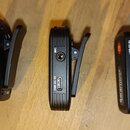 Tři černé kompaktní elektronické zařízení s připevněnými kovovými svorkami. Na dvou z nich jsou viditelné nápisy MIC u vstupu a USB DC 5V u portu. Tř…