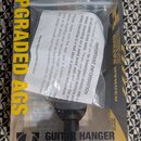 Fotografie znázorňuje držák na kytaru v původním balení. Na žlutém kartonu je nápis UPGRADED AGS, GUITAR HANGER a logo s textem HERCULES. Pod názvem…