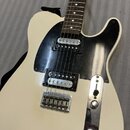 Bílá elektrická kytara s černým pickguardem a hnědým hmatníkem. Nástroj je vybaven dvěma humbuckery s chromovanými kryty a chromovaným mostem. Na těl…