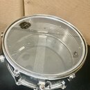 Průhledná blana na snare drum s kovovým obručím. Na blaně je černé kulaté logo MAPEX a v pravé části nápis UT MADE IN TAIWAN. Povrch blány vykazuje d…