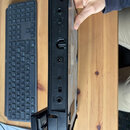 Fotografie zachycuje zadní panel černého elektronického zařízení, které drží ruka. Jsou zde viditelné konektory a nápisy: "OUTPUT", "INPUT", "MIDI IN…