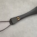 Černý, zakřivený předmět z plastu nebo kompozitního materiálu s kovými součástmi na jednom konci. Na horním okraji jsou umístěny čtyři kovové kolíky…