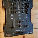 Černý DJ mixér značky ALLEN&HEATH, model Xone:23C. Na předním panelu jsou umístěny knofíky, posuvníky a tlačítka s nápisy jako MIX, MASTER, MONITOR,…
