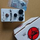 Bílý efekt pedál s nápisy THE WHITE ELK, SMALL FOOT a WREN and CUFF USA. Na horní straně jsou tři černé ovládací knoflíky s popisky VOLUME, TONE a DI…