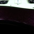 Detailní záběr na tělo elektrické kytary s tmavě fialovým metalizovaným lakem s třpytivým efektem. V horní části je vidět světle zelený pickguard s d…