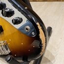 Detail spodní části trupu elektrické kytary s barevným přechodem od žluté přes oranžovou k hnědé a černé. Na povrchu jsou vidět tři černé oválné knof…