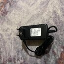 Černý síťový adaptér s plastovým povrchem a dvěma kabely. Na štítku je uveden název ROCKPOWER®, vstupní napětí Input: 100-240V~ 50/60Hz 0.3A a výstup…
