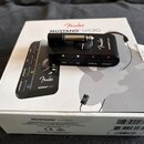 Na bílém kartonovém obalu s nápisy Fender MUSTANG MICRO je položen černý kompaktní kytarový zesilovač Mustang Micro. Zařízení má stříbrný konektor, o…