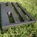 Černý kovový stojan nebo podložka s třemi vodorovnými mřížkovými plochami. Konstrukce je hranatá a povrch vykazuje drobné známky opotřebení v podobě…