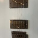Detail elektrické kytary s bílým povrchem. Nástroj má dva humbucker snímače v tmavě hnědé barvě, přičemž na spodním je čitelný nápis INF2. V dolní čá…