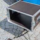 Černý transportní case z dřevotřsky s hliníkovým profilem a kovovými rohy. Case je otevřený, vnitřní prostor je černý. Na pravém boku je vidět vestav…
