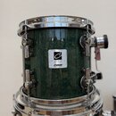Zelený buben s tmavší texturou povrchu a chromovaným obručováním. Na korpusu jsou dvě nálepy s nápisy „DESIGNER SERIES made in germany“ a „SONOR MADE…