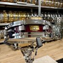 Vínový malý buben s chromovaným obručováním a mechanismy, umístěný na chromovaném stojanu. Na korpusu je zlatý štítek s nápisy TAMA, SNARE DRUM a Ser…