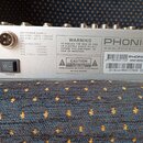 Záběr na zadní stěnu stříbrného elektronického zařízení. Je zde vidět napájecí konektor, vypínač s nápisem POWER a logo PHONIC s webovou adresou WWW.…