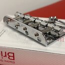 Kromové kobylky pro elektrickou kytaru s šesti sedly a ladicími šrouby. Nástroj leží na bílém kartónovém obalu, na kterém je červeným písmem nápis GO…