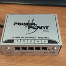 Stříbrný kovový napájecí adaptér s nápisem POWER PLANT Junior. Na horní straně je text 9 VOLT DC OUTPUTS - ISOLATED a čísla 1 až 5 nad odpovídajícími…