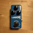 Modrý efekt pedál s nápisy FLASHBACK MINI a tc electronic. Na horní části jsou tři černé ovládací knoflíky s popisky DELAY, F. BACK a LEVEL. V dolní…
