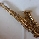 Zlatý saxofon s kovovým povrchem. Na těle nástroje nejsou viditelná žádná loga, značky ani názvy modelů. Povrch je lesklý a bez viditelného opotřeben…