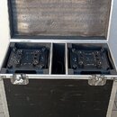 Otevřený černý transportní kufr s hliníkovými hranami a koly, uvnitř kterého jsou ve dvou oddělených přihrádkách umístěna dvě černá zařízení. Na horn…
