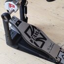 Krytý basový pedál s černým základem a stříbrným šlapadlem. Na šlapadle je viditelné logo TAMA a nápis The Legend in Innovation. Na horní části mecha…