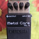 Kytarový efekt pedál značky BOSS, model Metal Core ML-2. Zařízení má černé kovové tělo s bílým nápisem a čtyři ovládací knoflíky na stříbrném horním…