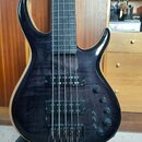 Tmavě hnědá basová kytara s výraznou strukturou dřeva a černým hardwarem. Na horním snímači je nápis "Sire Marcus Miller". Nástroj má dva snímače, čt…