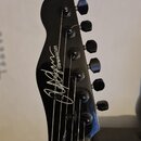 Černá hlava elektrické kytary s šesti ladicími kolíky. Na povrchu je bílý nápis v rukopisném stylu a vedle něj text CHAYYANN GUITARS. Povrch je leskl…