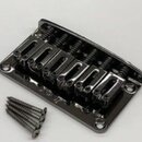 Černý kovový kobylník pro elektrickou kytaru s šesti sedly a viditelnými pružinami. Vedle kobylníku je položeno deset černých montážních šroubů. Povr…