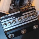 Stříbrný efektový pedál s černým spodním rámem a nápisem BOSS. Na horní části je uveden model Delay Machine DM-101 s ovládacími knoflíky pro MOD RATE…