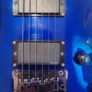 Detail modré elektrokitary se dvěma černými humbuckery. Horní snímač má v pravém horním rohu nápis ESP, dolní snímač má v pravém dolním rohu nápis EM…