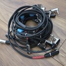 Svršek dřevěné podlahy, na které leží několik černých kabelů s konektory. Na jednom z kabelů je viditelný bílý nápis GERMANY MICROPHONE CME-312. Někt…
