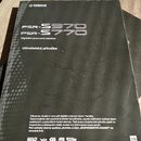 Fotografie znázorňuje černý tištěný manuál s nápisem YAMAHA v horní části. Uprostřed je uveden text PSR-S970 a PSR-S770, pod kterým následuje popis D…