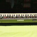 Černý elektronický klavír s bílými a černými klávesami. Na přední straně je umístěno bílé logo YAMAHA. Nástroj obsahuje řadu ovládacích tlačítek a po…