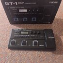 Černý kytarový procesor BOSS GT-1 v originální krabici. Na přístroji i na obalu jsou viditelné nápisy BOSS GT-1 GUITAR EFFECTS PROCESSOR a logo COSM.…