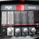 Černý kytarový procesor s nápisem RP 255 MODELING GUITAR PROCESSOR. V horní části je červený digitální displej zobrazující číslo 3. Panel obsahuje řa…
