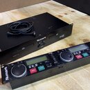 Dvě černé elektronické zařízení značky Numark na dřevěném stole. Horní jednotka má nápisy Numark a CDN22, v přední části je slot pro disk a ovládací…
