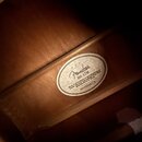 Detail vnitřní části dřevěného akustického nástroje s nalepeným oválným štítkem. Na štítku je logo Fender, označení modelu DG-17M a nápis Made in acc…